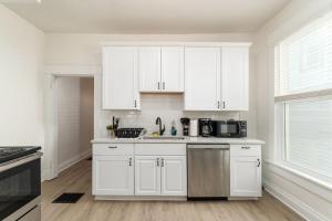 a white kitchen with white cabinets and a sink at Housepitality - The Madison House - Brand New in Columbus