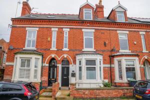 a red brick house with cars parked in front of it at Comfortable stylish room Pass the Keys in Beeston
