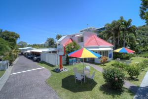 ein Haus mit 2 Sonnenschirmen, einem Tisch und Stühlen in der Unterkunft Port Douglas Motel in Port Douglas