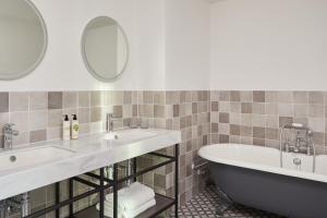 考文垂的住宿－Hotel Indigo Coventry, an IHG Hotel，浴室配有两个盥洗盆和浴缸。