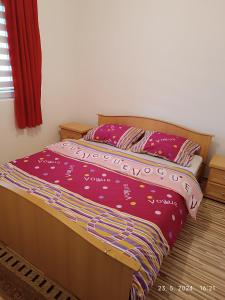 a bed with a red comforter and two pillows at 3-Bedroom NewHome in Mostar