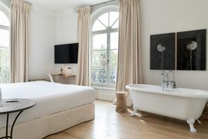 塞维利亚Hotel Tayko Sevilla的卧室配有床、浴缸和窗户。