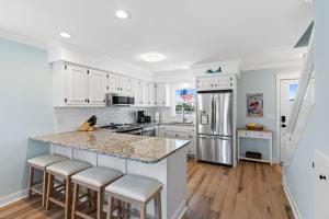 a kitchen with white cabinets and a kitchen island with bar stools at Mom's Gift 256-B Brunswick Ave West home in Holden Beach
