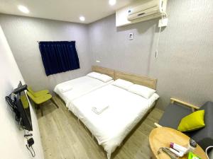 Schlafzimmer mit einem Bett mit weißer Bettwäsche und Kissen in der Unterkunft Fengchia Aliproda in Taichung