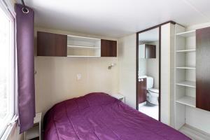 羅科比列爾的住宿－Camping 3* Les Templiers，一间卧室配有一张紫色的床和一个卫生间