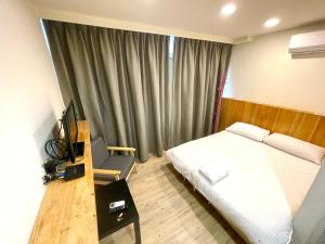 Schlafzimmer mit einem Bett und einem Schreibtisch mit einem TV in der Unterkunft Fengchia Aliproda in Taichung