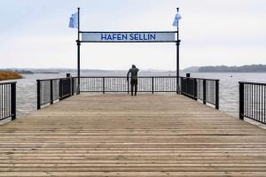 een man op een pier naast het water bij Ferienwohnung 05 Am Selliner See in Ostseebad Sellin