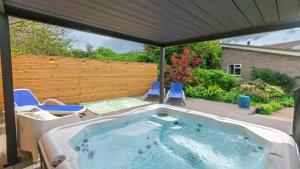 a hot tub on a patio with a wooden fence at Ladywell Croyde - Super stylish large home with pool table, woodburner, pizza oven and Hot Tub Option, Sleeps 12 in Croyde