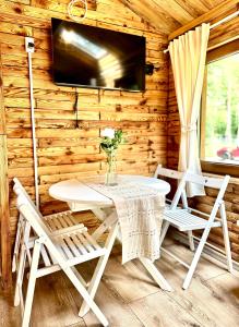 Cabaña de madera con mesa, sillas y TV en Urocza chatka w lesie nad wodą, en Skubianka