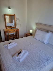 um quarto com uma cama com toalhas e um espelho em Zeus Guesthouse em Panagia