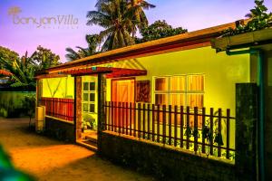 una pequeña casa amarilla con una valla delante en Banyan Villa Maldives Dhangethi, en Dhangethi