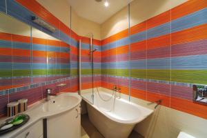 La salle de bains colorée est pourvue d'une baignoire et d'un lavabo. dans l'établissement Boutique Hotel Light House Jurmala, à Jurmala