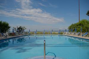 a large blue swimming pool with chairs and the ocean at Hotel Vela D'oro ***S in Bardolino