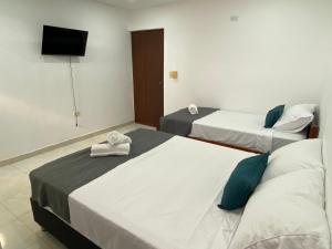 two beds in a hotel room with a television at 22 Guest House in Santa Marta