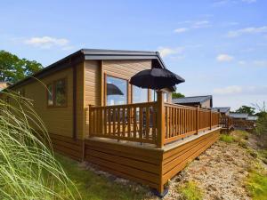 a cabin with an umbrella on a deck at E7 Roebeck Country park in Ryde