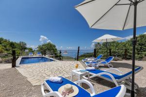 a group of chairs and umbrellas next to a pool at Stonehouse Residence in Makarska