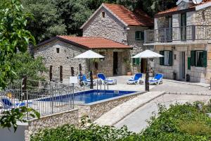 a swimming pool with chairs and umbrellas in front of a building at Stonehouse Residence in Makarska