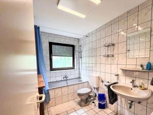 a bathroom with a sink and a toilet and a tub at Apartment Ferienapartments Adenau-4 by Interhome in Adenau