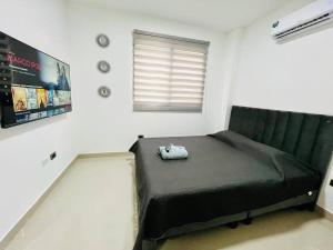 a bedroom with a bed with a black blanket and a window at Departamento 2 Habitaciones con Balcón a 10min Consulado Americano in Guayaquil