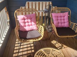 two wicker chairs with pink pillows sitting on a deck at Holiday Home Willa klaara by Interhome in Patajoki