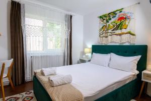 um quarto com uma cama com uma cabeceira verde e uma janela em Apartament Corina cu parcare em Bistriţa