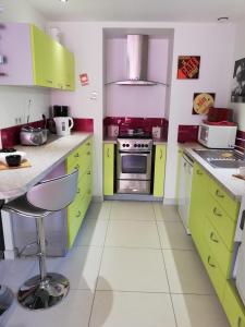 a kitchen with yellow and green cabinets and a stove at coin de paradis 3 chambres in Fouras