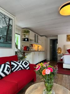 ein Wohnzimmer mit einem roten Sofa und einer Vase aus Blumen in der Unterkunft Boat no Breakfast in Amsterdam