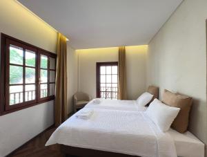 1 dormitorio con 2 camas y 2 ventanas en Viva Properties, en Ouranoupoli