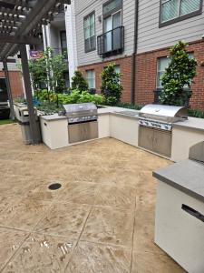 a patio with three barbecueurgers in front of a building at Cozy 1bedrm/1bed/air mattress in Dallas