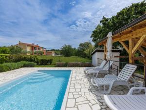 einem Pool mit Stühlen und einem Sonnenschirm neben einem Haus in der Unterkunft Holiday Home Ema by Interhome in Nova Vas