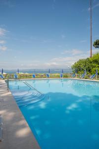 a large blue swimming pool with blue chairs and the ocean at Hotel Vela D'oro ***S in Bardolino