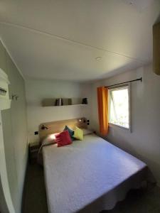 Dormitorio pequeño con cama con almohadas coloridas en Camping Villaggio Il Collaccio, en Preci