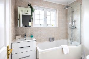 Un baño con bañera, lavabo y ducha. en Windrush Lake 41, Kingfisher House, en South Cerney 21 fotos más
