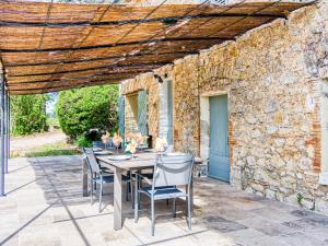 una mesa y sillas en un patio con una pared de piedra en Holiday Home La Ferme by Interhome en Besse-sur-Issole