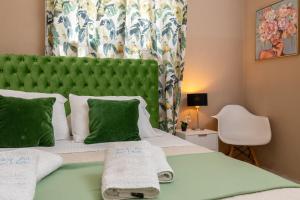 sypialnia z zielonym zagłówkiem i łóżkiem z ręcznikami w obiekcie Family Inn Apartments&suites w mieście Neos Marmaras