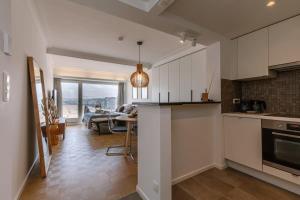 een keuken met witte kasten en een woonkamer bij Stunning studio with sea-view and terrace in Knokke-Heist