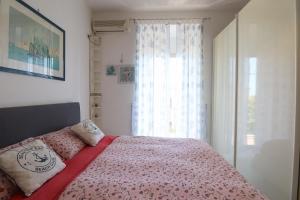 een slaapkamer met een bed met een roze deken en een raam bij La Maison à la Plage - Vista mare & 5min Spiaggia in Santa Marinella
