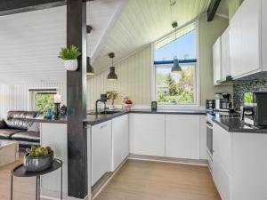 a kitchen with white cabinets and a large window at Holiday Home Bryti - 500m from the sea in NE Jutland by Interhome in Hals