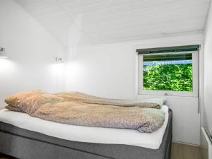 a bed in a white room with a window at Holiday Home Bryti - 500m from the sea in NE Jutland by Interhome in Hals