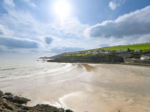 a sandy beach with the ocean and houses in the background at Holiday Home Dolphin Cottage by Interhome in Mevagissey +56 photos