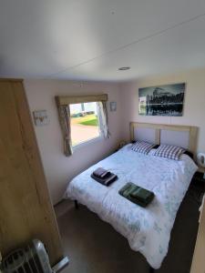 um quarto com uma cama e uma janela em G & M Static Caravan Edinburgh em Port Seton