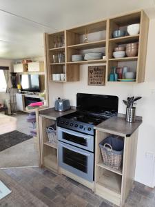 a kitchen with a stove and wooden cabinets at G & M Static Caravan Edinburgh in Port Seton