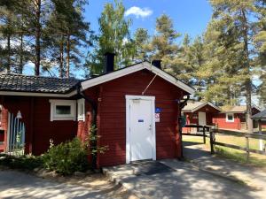 um pequeno barracão vermelho com uma porta branca em Hyltena Stugby em Jönköping
