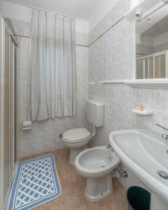 Un baño blanco con inodoro y lavabo. en Residence La Serenissima, en Caorle 52 fotos más
