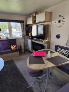a living room with a table and a tv at G & M Static Caravan Edinburgh in Port Seton