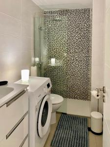 een badkamer met een toilet en een douche met een wasmachine bij Tanife 310 - Playa del Ingles comfort Suite with Sunset view in Playa del Inglés