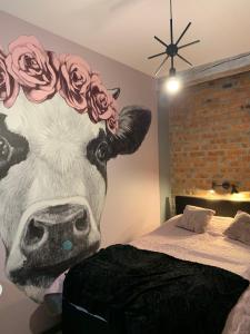 a mural of a cow with roses on its head next to a bed at Siedlisko Kępina Zdrój in Ostrów