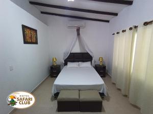 a bedroom with a bed with a white bedspread at Hotel Safari Club Robore in Roboré