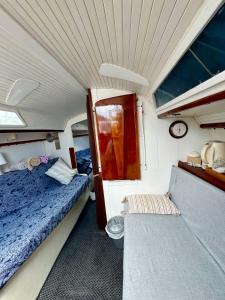 Habitación pequeña con cama y banco en un barco en Vive la experiencia de dormir acunado por las olas cerca de Barcelona en Castelldefels