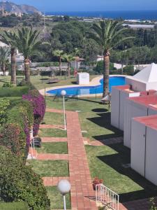 un jardín con piscina y palmeras en Villa Alhambra, en Nerja